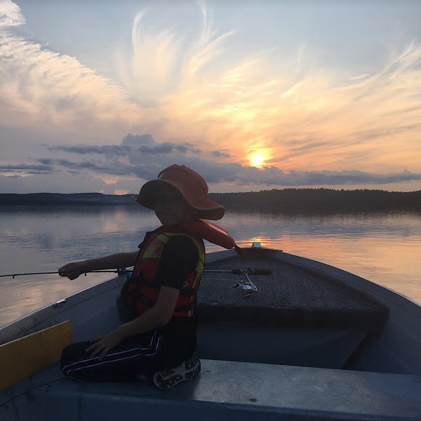 Fishing out of boat with family at sunset